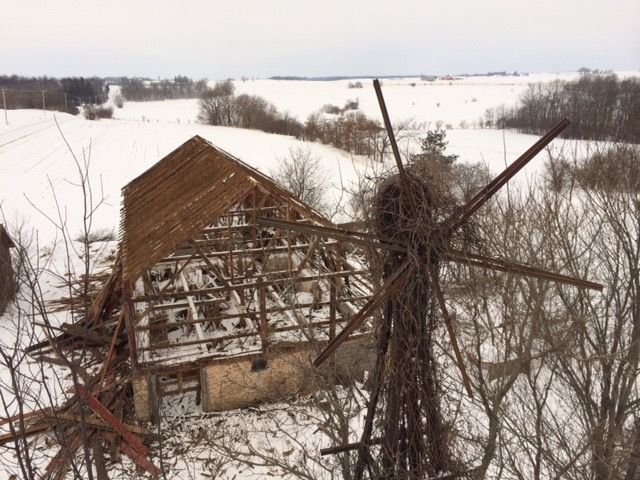 A Wisconsin barn part-way through teardown in winter, timber frame exposed